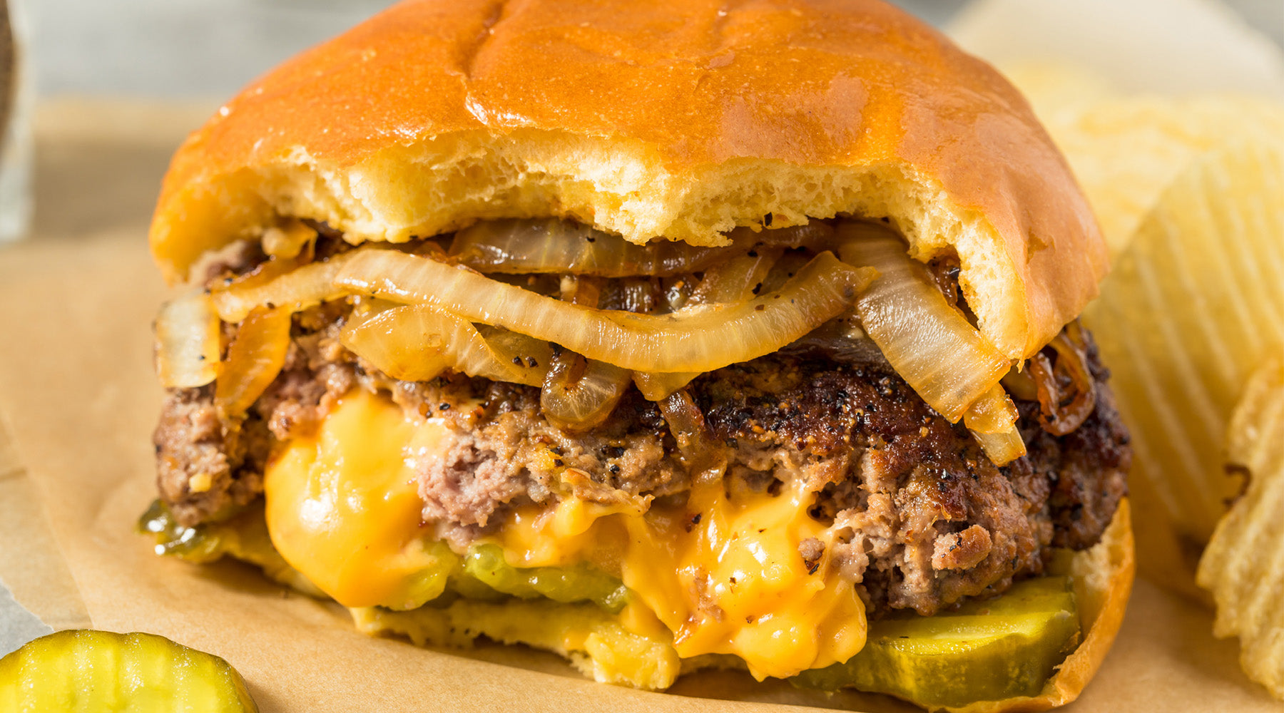 Burger with cheese in the middle, topped with onions and pickles