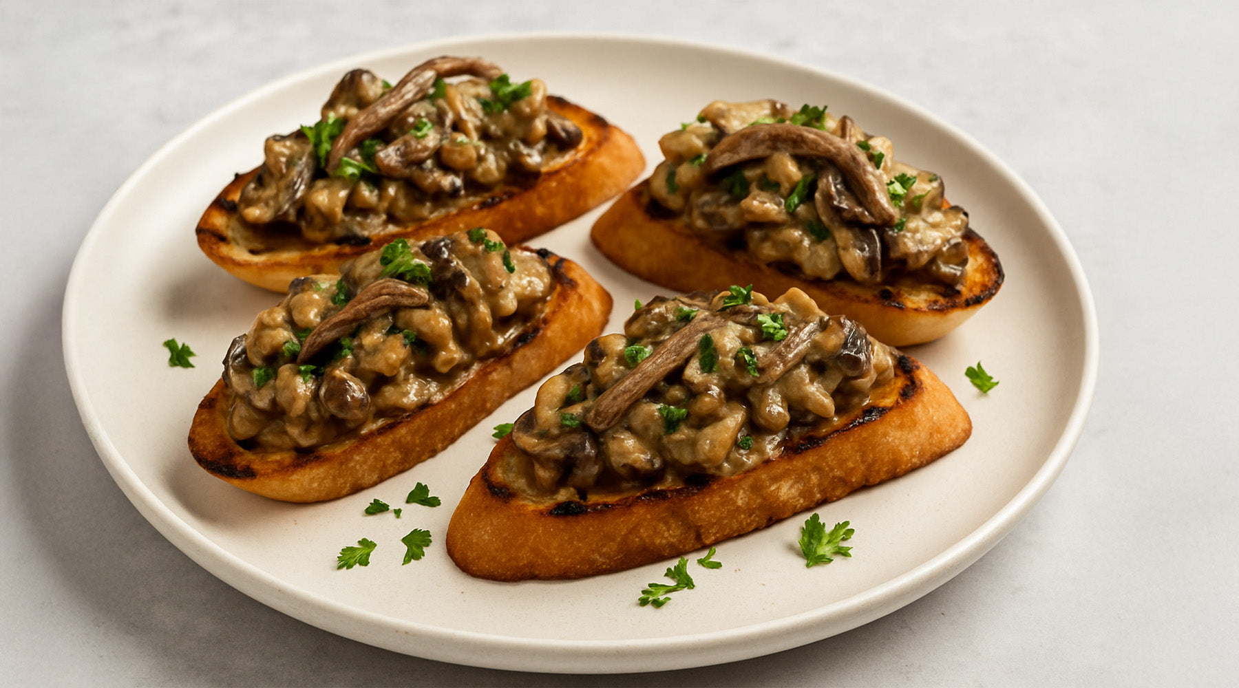Spicy and Creamy Wild Mushrooms with Anchovy Bruschetta on a white plate